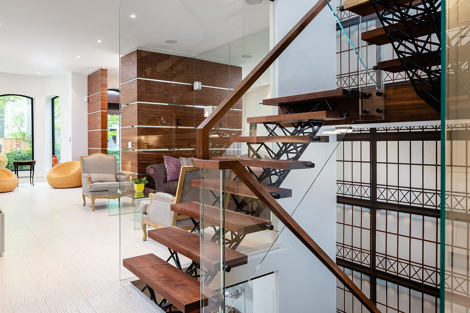 Black steel lattice stair railing with walnut treads and glass balustrade, an antique gilt clock mounted on the decorative wire panel.