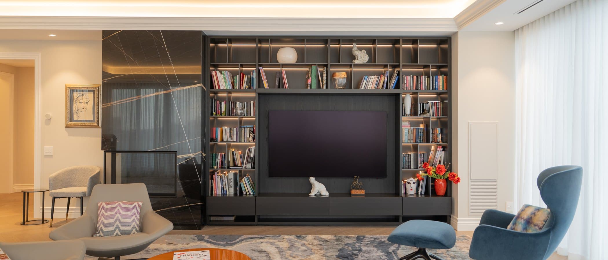 Living room with a custom millwork media wall and layered lighting in a whole home renovation