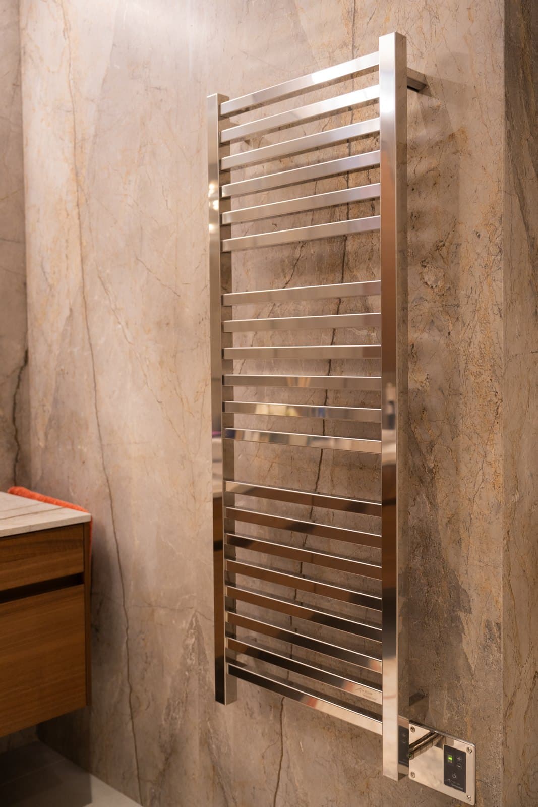 Bathroom detail with a polished towel warmer against large format stone