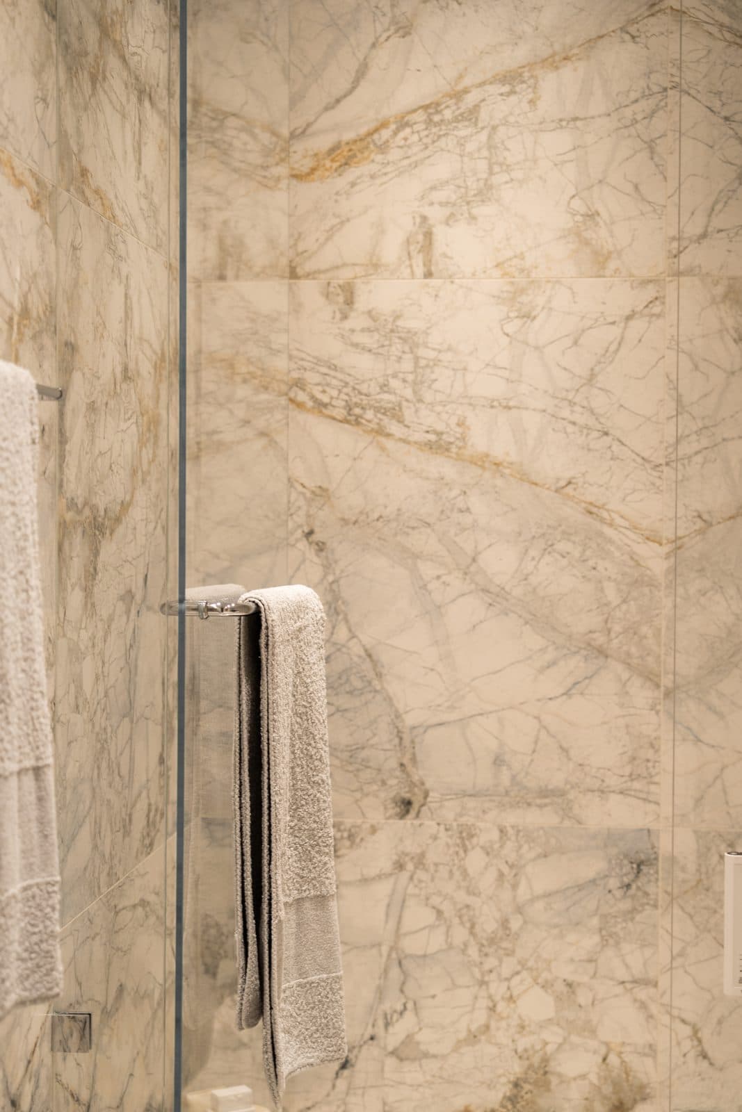 Book matched marble walk in shower behind frameless glass