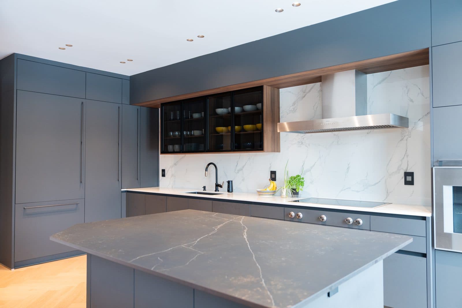 Kitchen island in dark veined stone with charcoal cabinetry beyond
