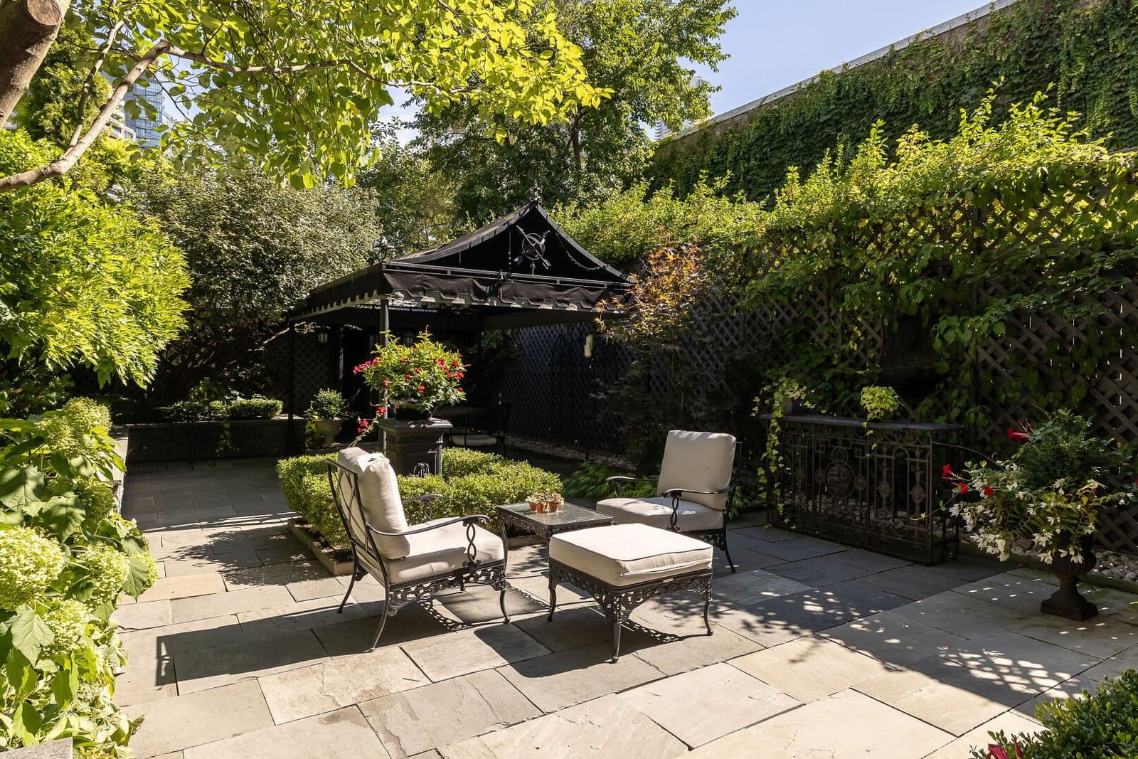 Walled garden courtyard with mature planting and a covered terrace