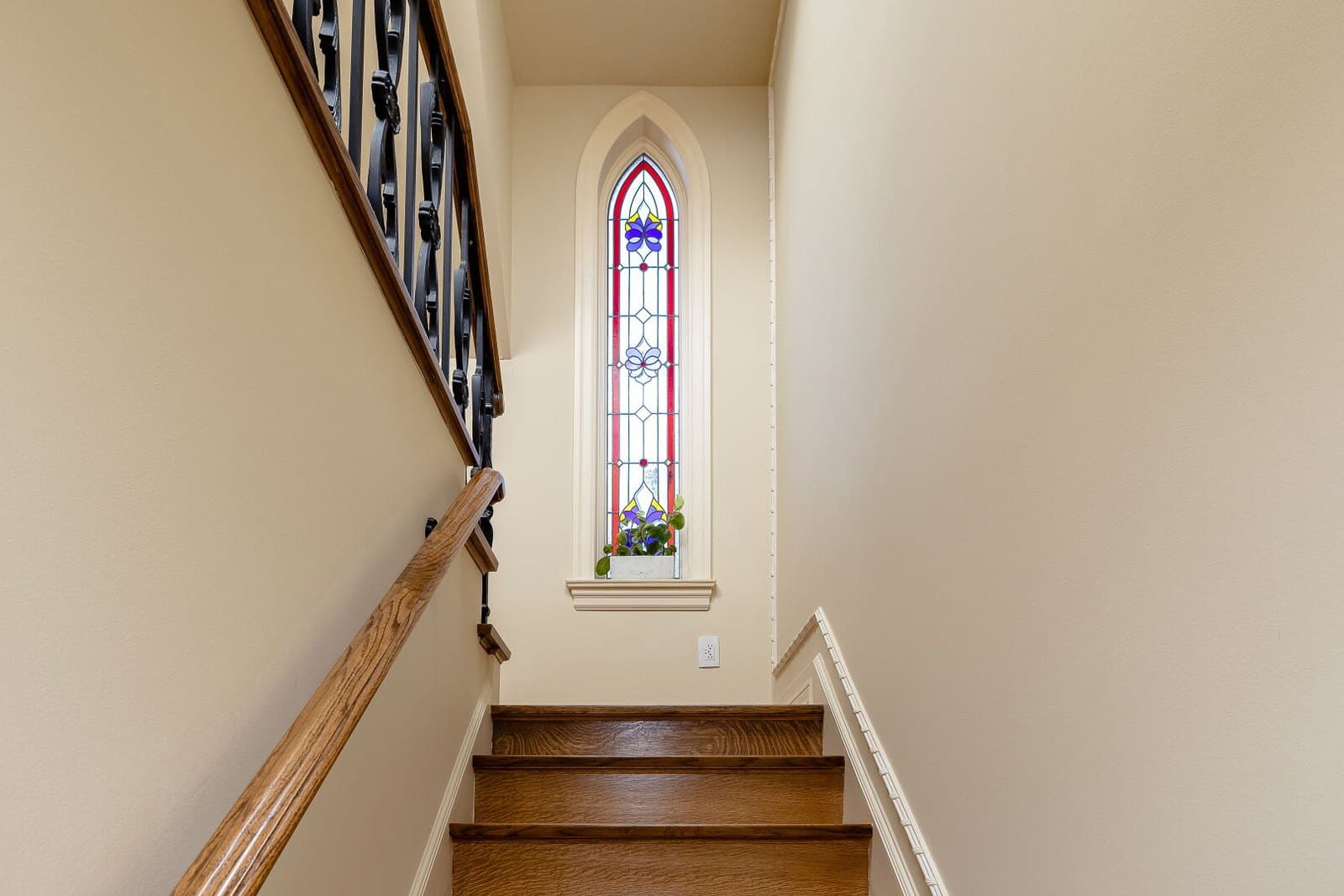 Stairwell illuminated by a tall stained glass window