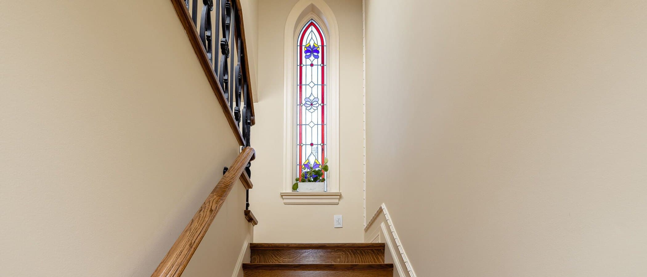 Stairwell illuminated by a tall stained glass window