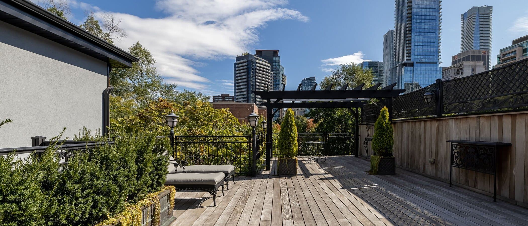 Rooftop terrace in wood decking with a pergola and the city skyline beyond