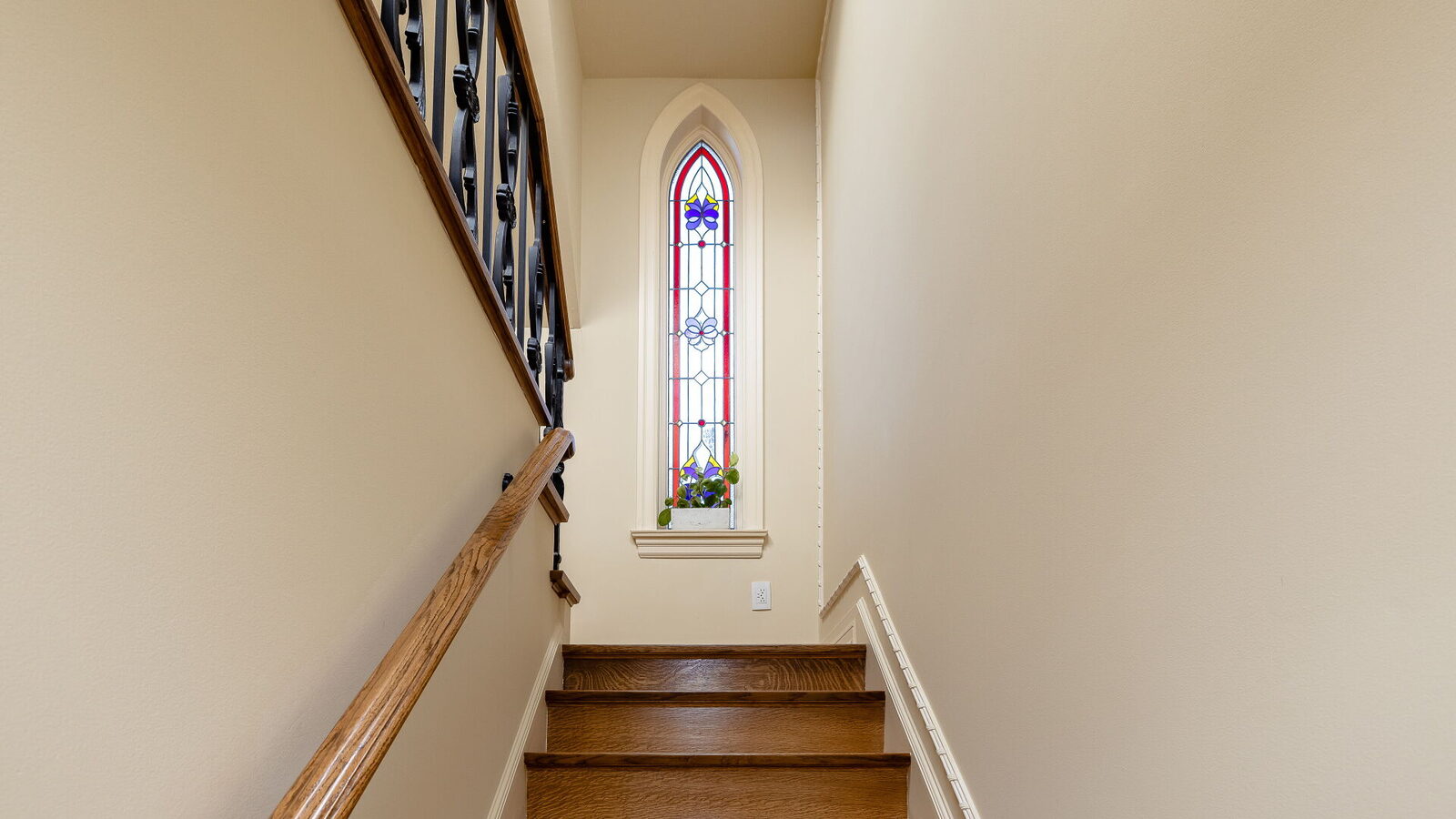 Stairwell illuminated by a tall stained glass window