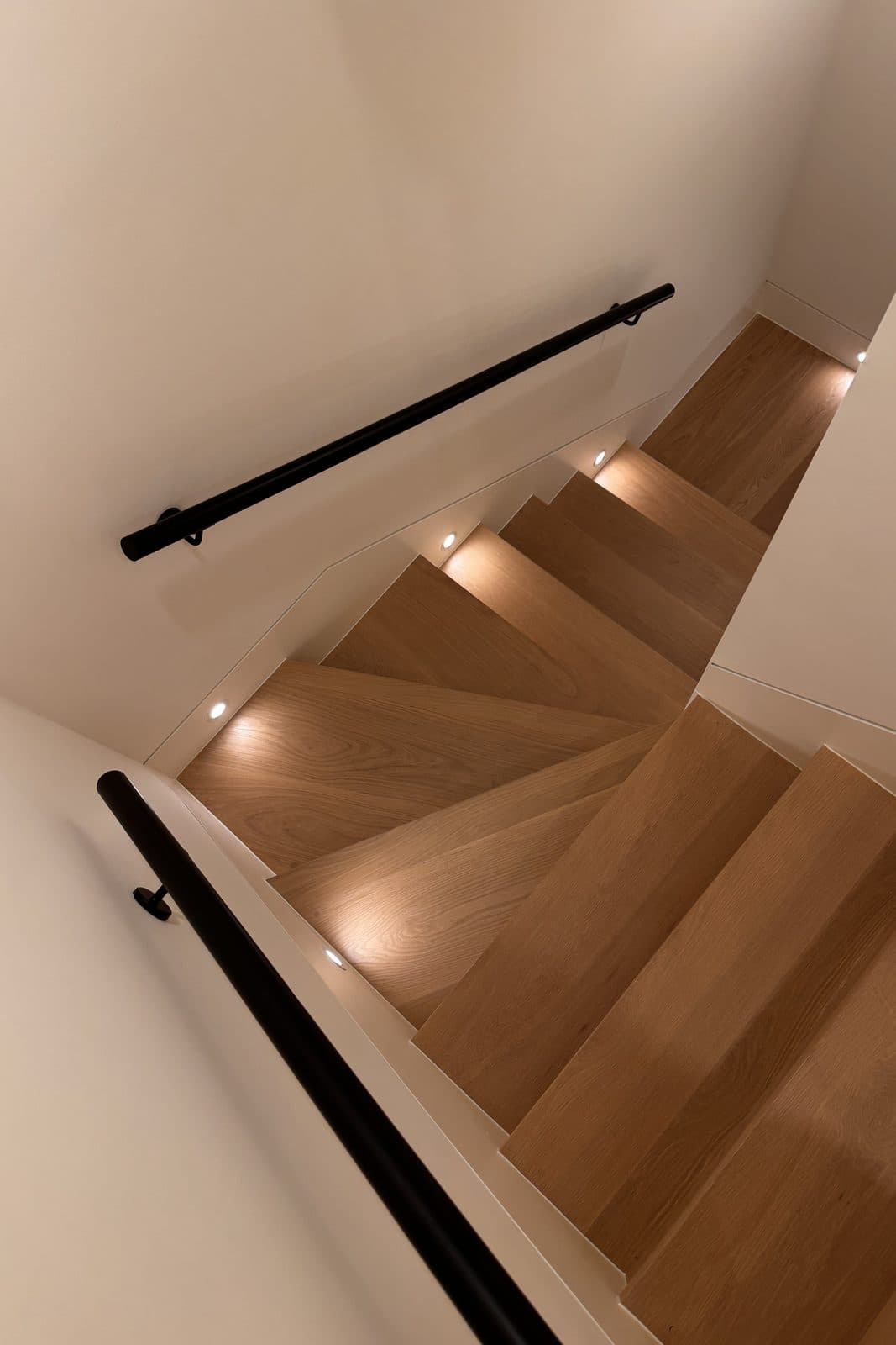 Overhead view of an oak staircase with a black steel handrail