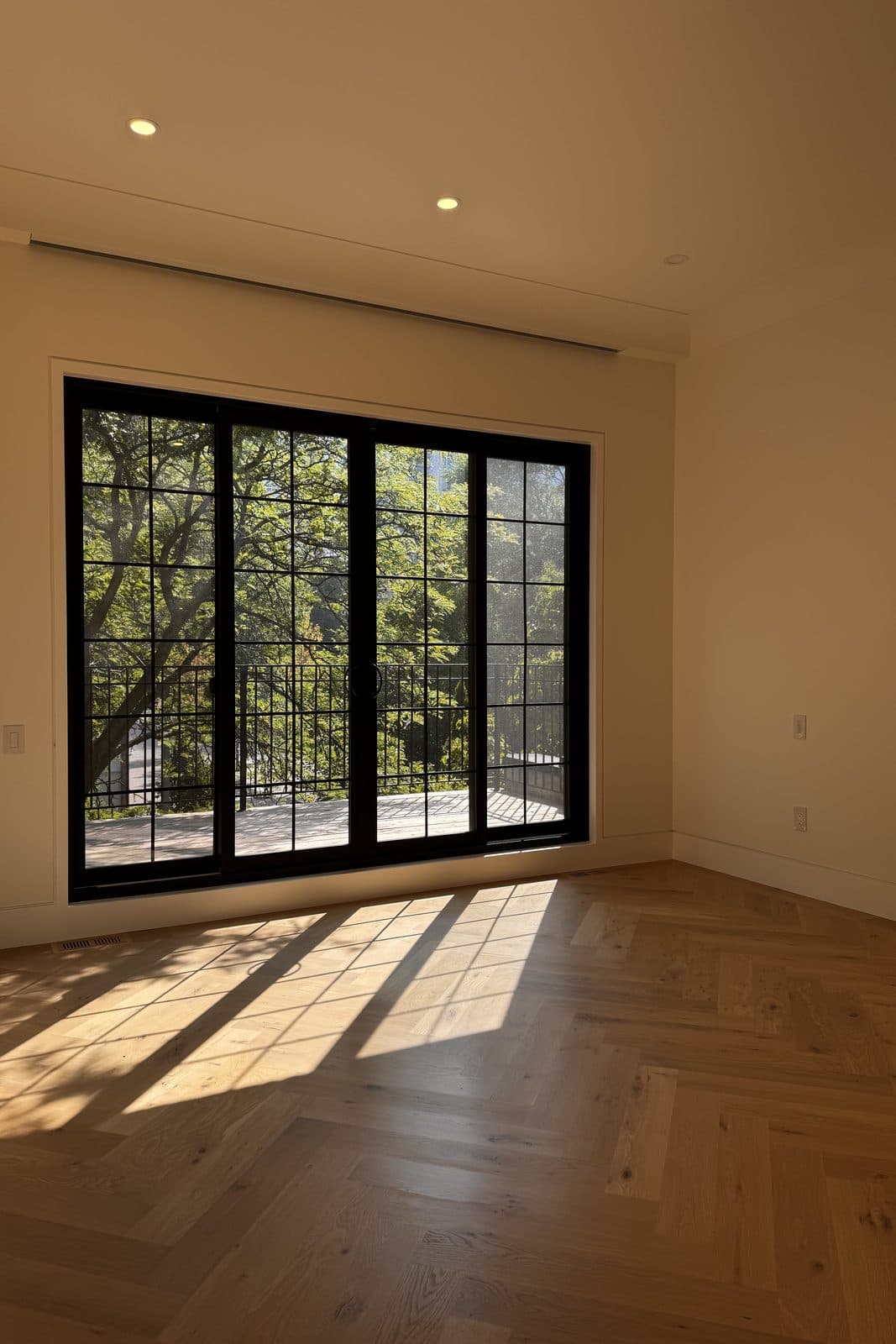 Sunlit room with tall black-framed windows over a herringbone floor