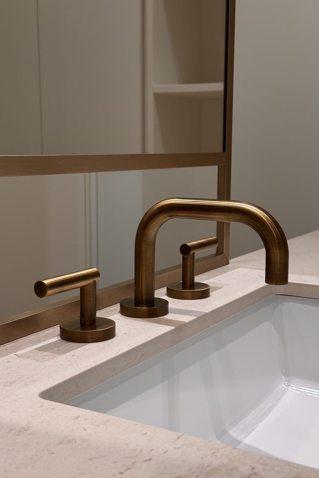 Detail of a wall-mounted brass faucet over a stone sink