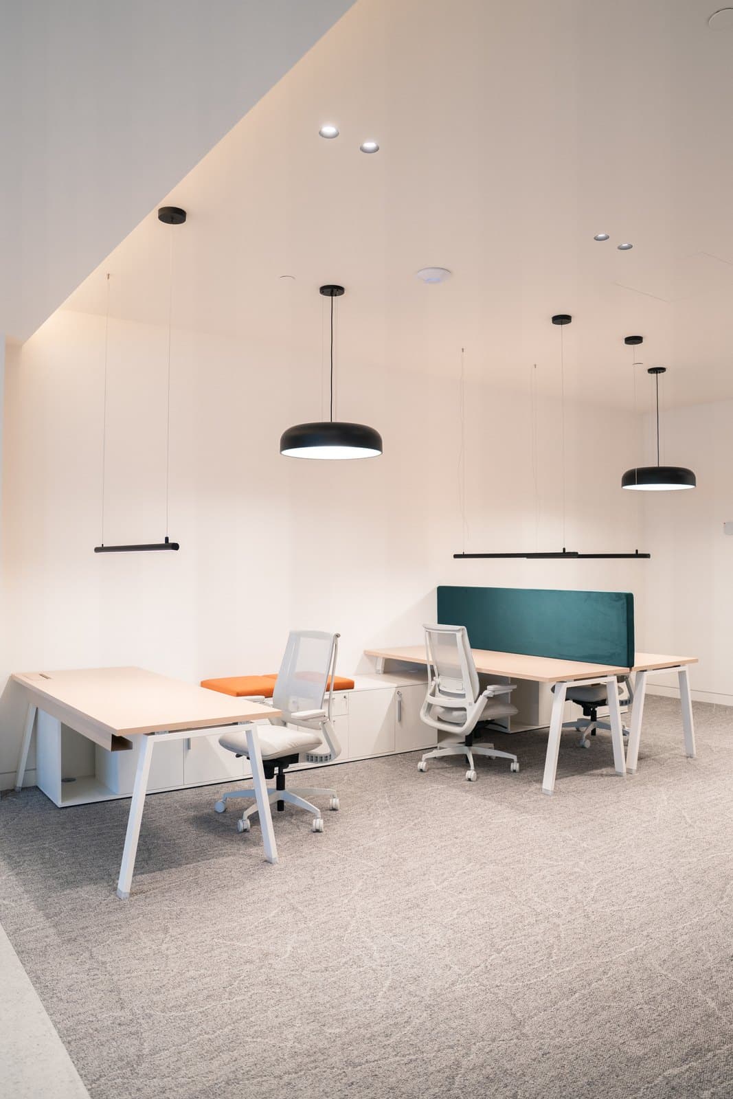 Workstation cluster with a green felt divider in a bright daylit office