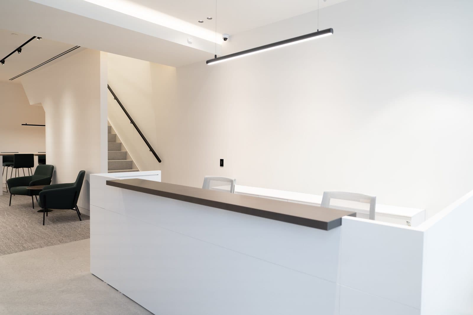 Reception desk beside the stair with green lounge chairs