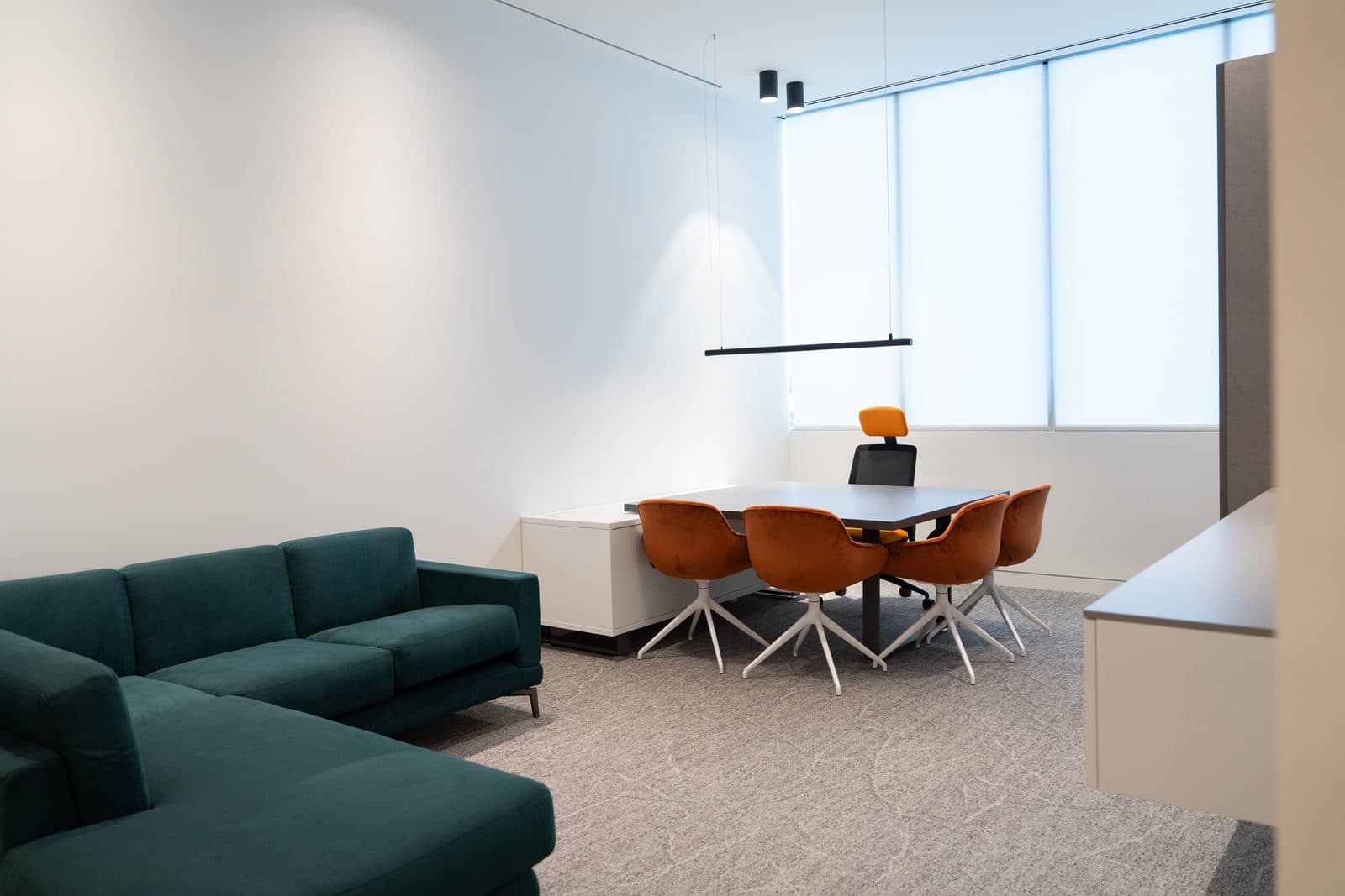 Lounge with a teal sectional and orange swivel chairs