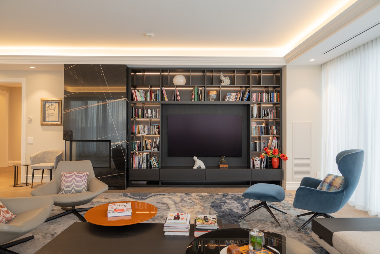 Library wall with built-in walnut shelving, art books and a pair of armchairs