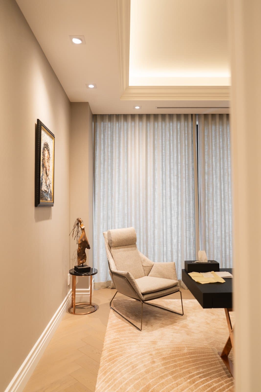 Sitting area with a lounge chair, layered drapery and cove lighting