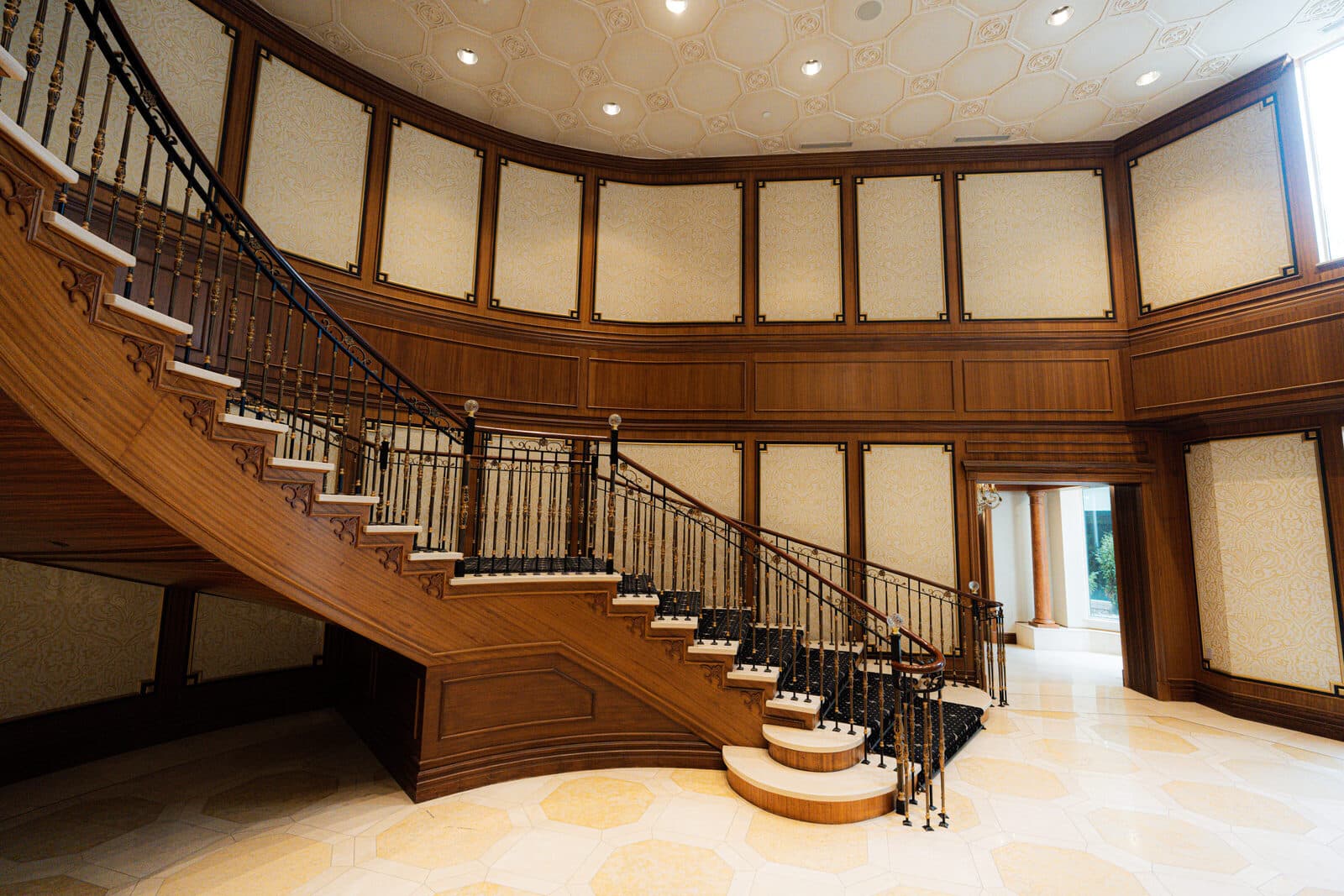 Curved staircase and wrought iron balustrade beneath panelled walls