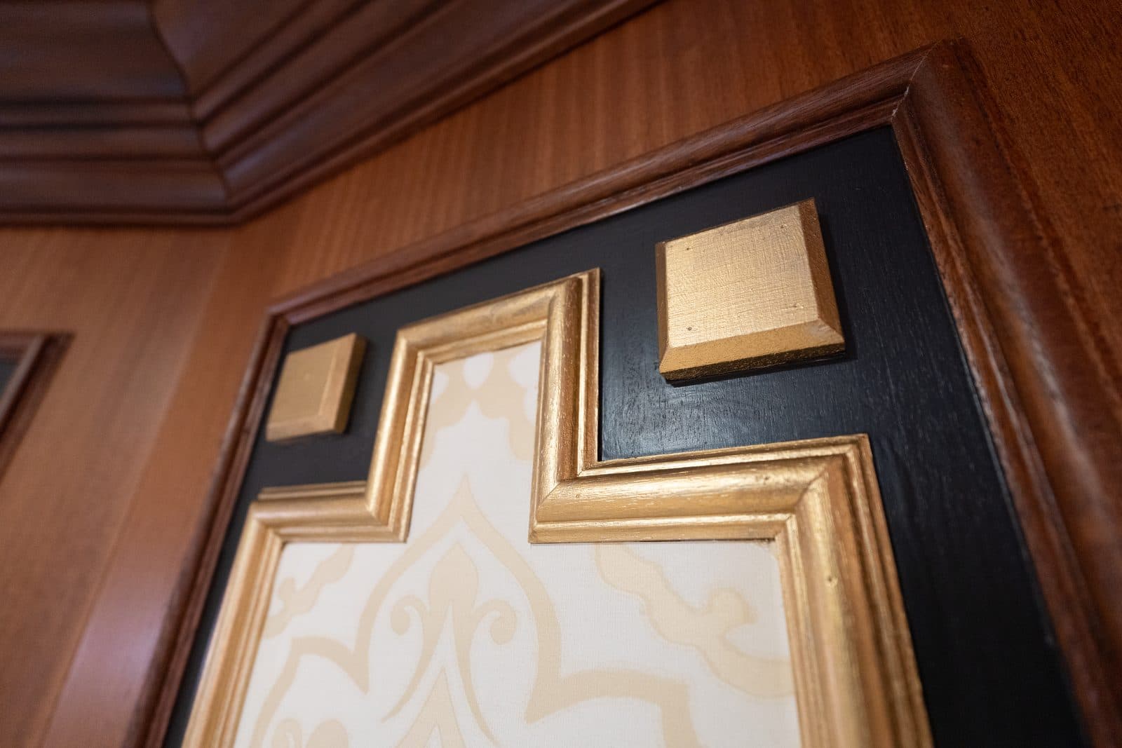 Gilt corner detail where mahogany trim meets black lacquer