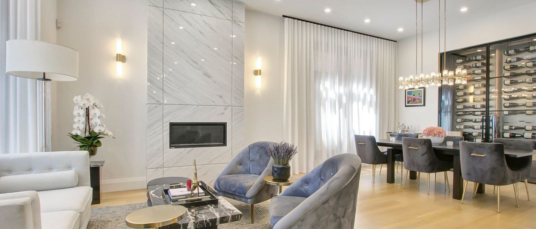 Living room with a marble fireplace and a glass enclosed wine display in a finished Leman renovation