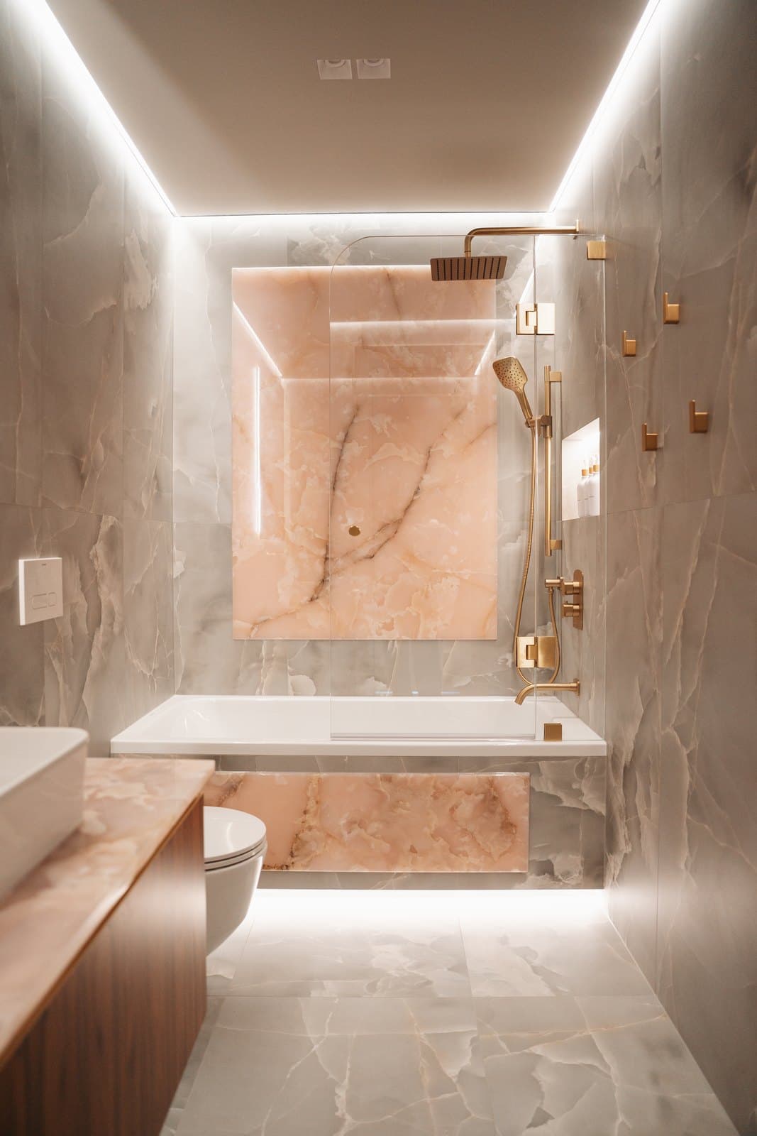 Onyx toned bathroom with a stone clad tub and warm brass hardware