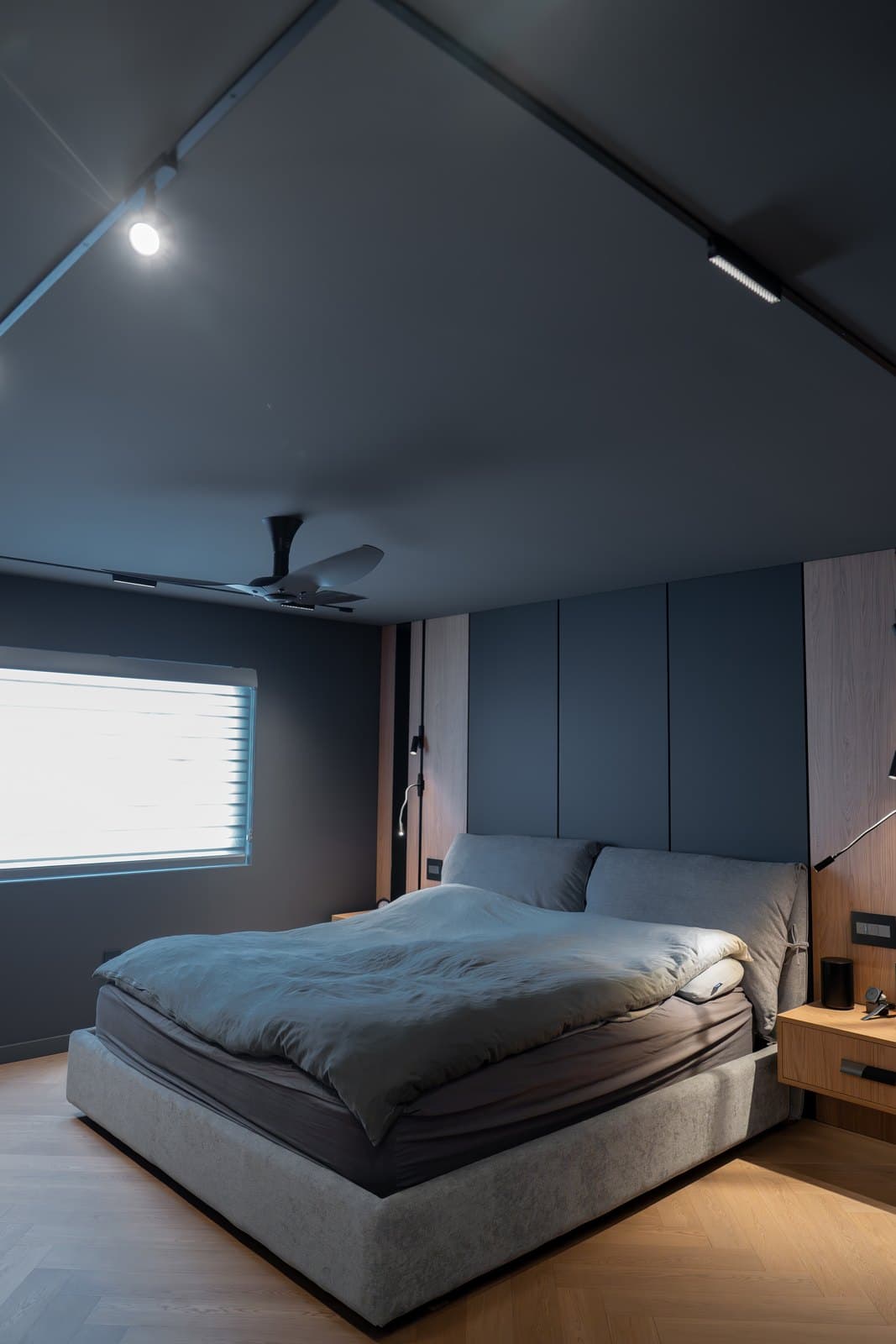 Bedroom in deep grey tones with a low platform bed and recessed lighting