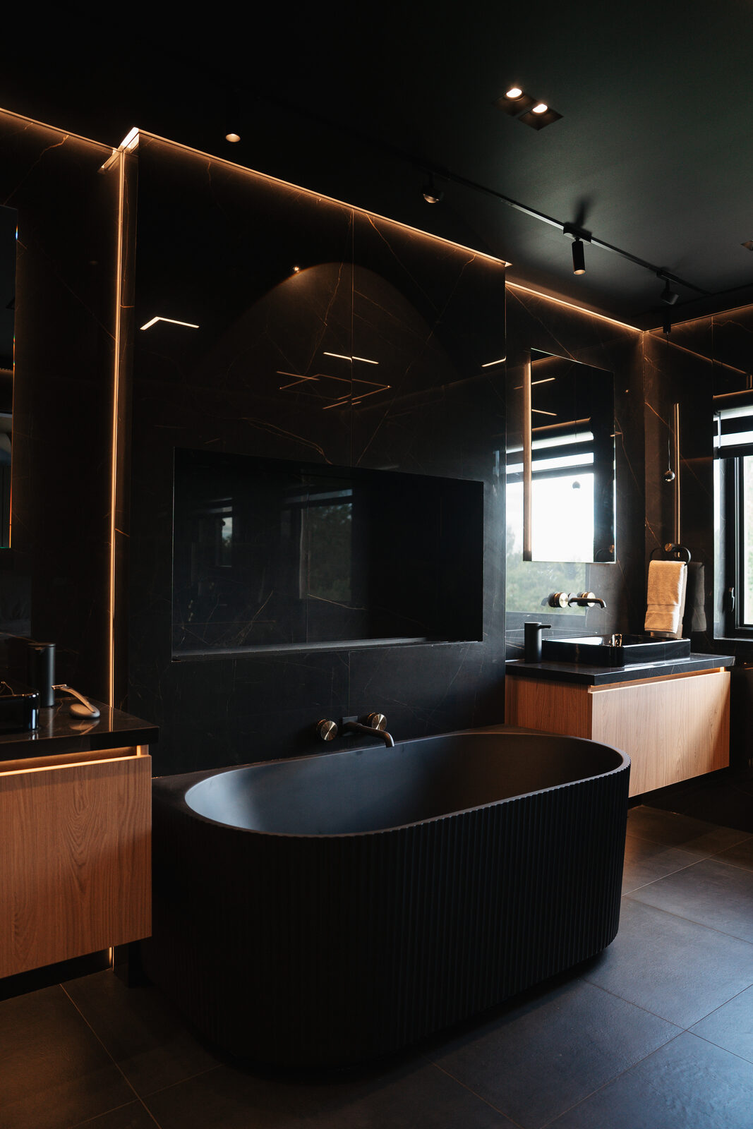 Fluted freestanding tub beneath a garden window in the black stone bath