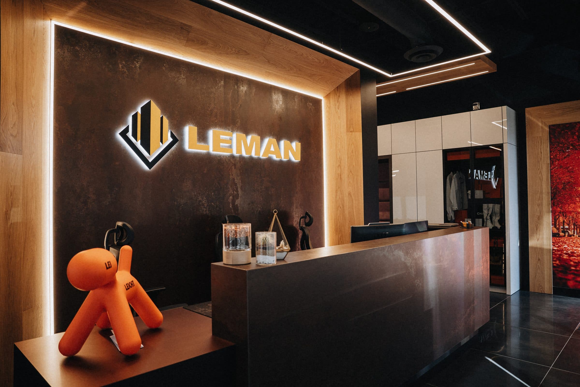 Reception desk beneath the illuminated Leman sign with a sculptural mascot and a merchandise display closet beyond