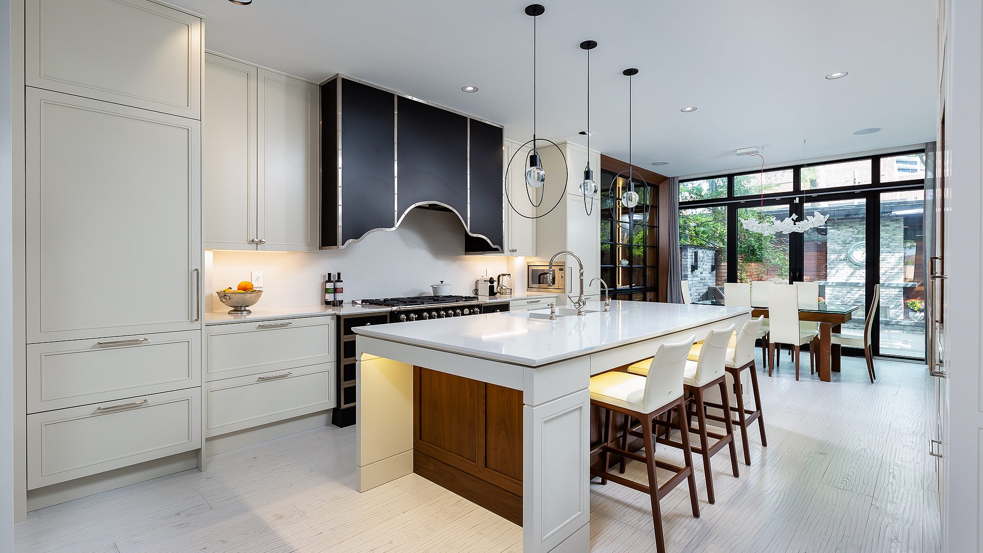 Sculpted steel range hood anchoring the kitchen with the garden framed beyond