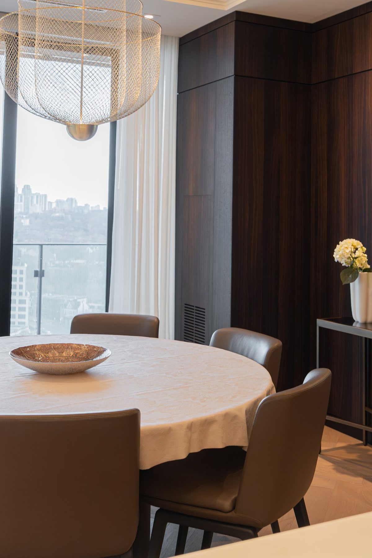 Dining room in walnut panelling with a round brass mirror and the city beyond
