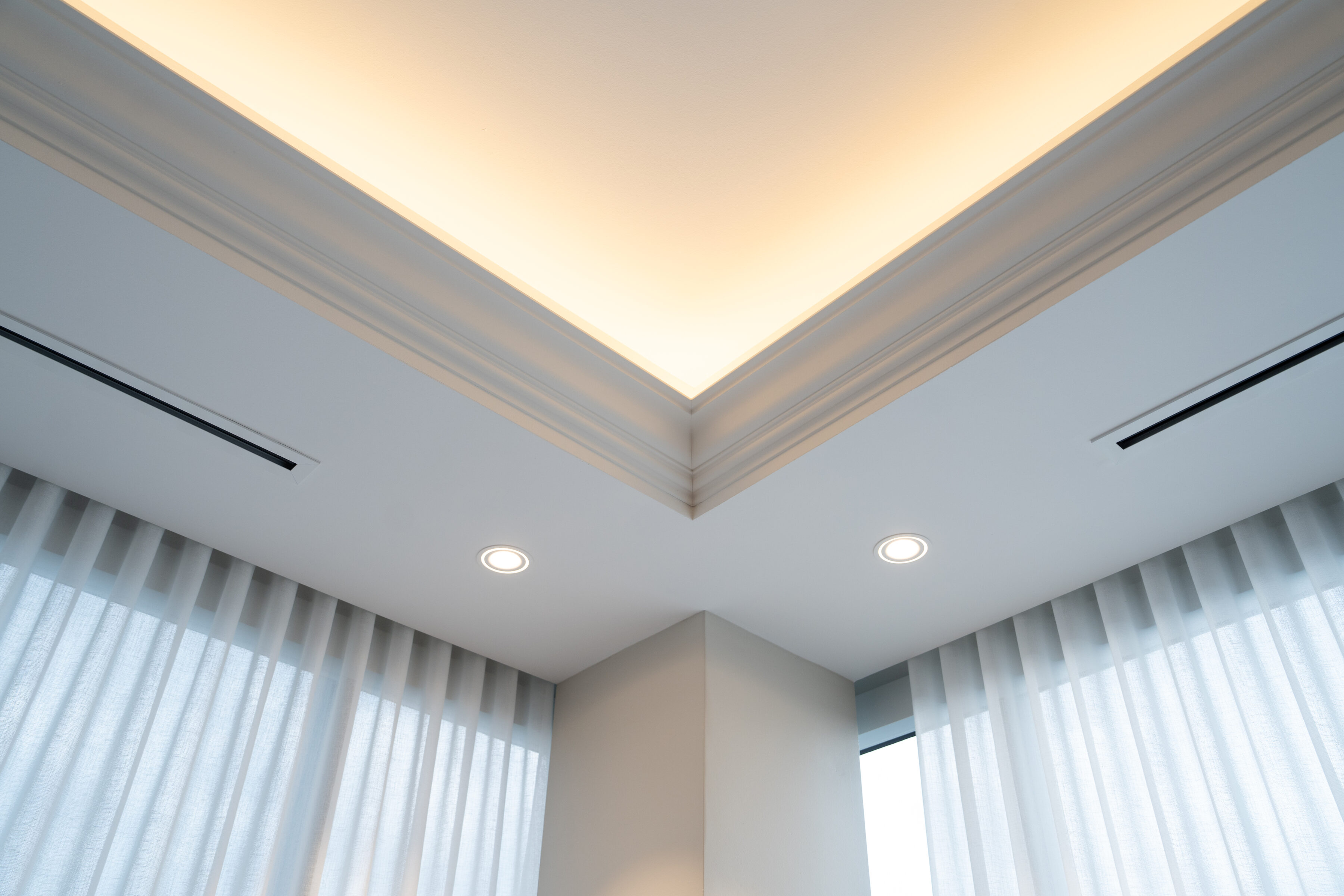 Lit cove ceiling framing sheer drapery in the primary suite