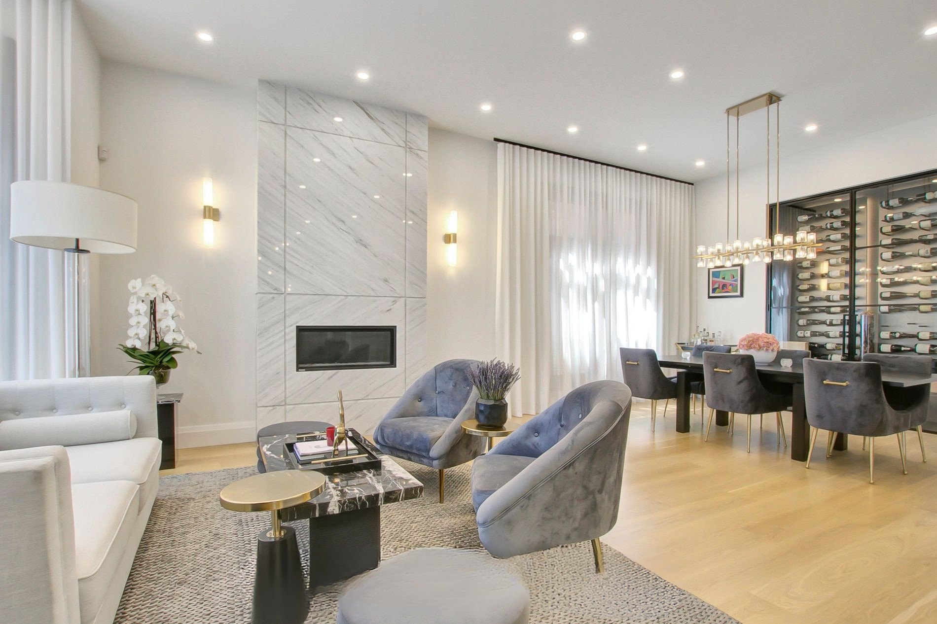 Living room with a slab marble fireplace facing a glass fronted wine wall